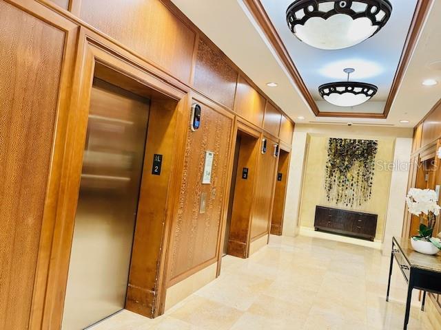 hallway with a raised ceiling and elevator