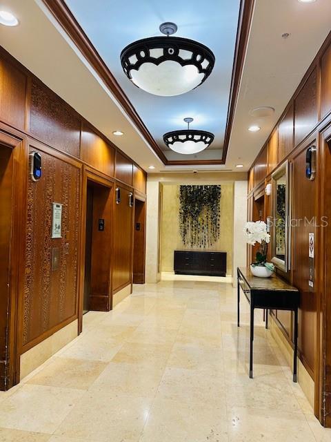 corridor featuring a raised ceiling and ornamental molding