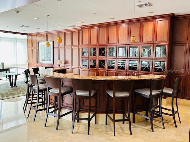 bar with light stone countertops and pendant lighting