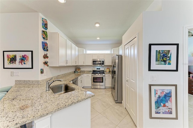 kitchen featuring appliances with stainless steel finishes, sink, white cabinets, kitchen peninsula, and light stone countertops