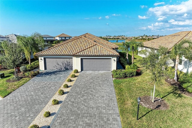 view of front of property with a garage, a front lawn, and a water view