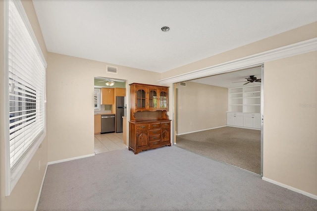 interior space with ceiling fan, light colored carpet, and built in features