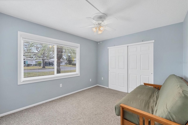 living area featuring ceiling fan, carpet flooring, and a textured ceiling