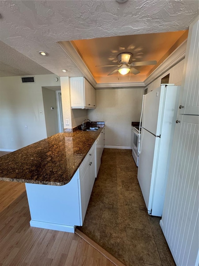 kitchen with white cabinetry, white appliances, kitchen peninsula, and sink