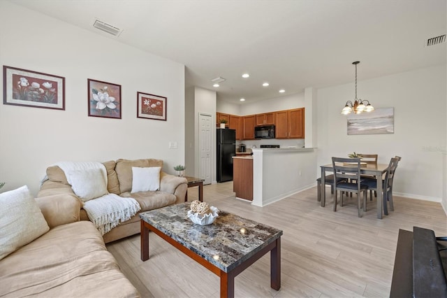 living room with an inviting chandelier and light hardwood / wood-style floors