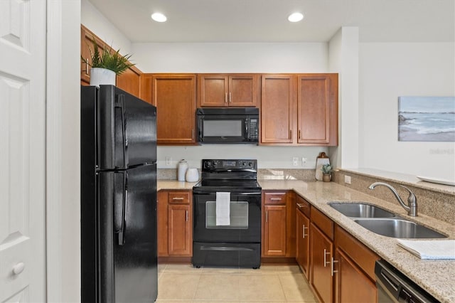 kitchen featuring light stone counters, sink, light tile patterned floors, and black appliances