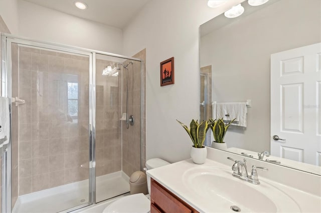 bathroom featuring a shower with door, vanity, and toilet