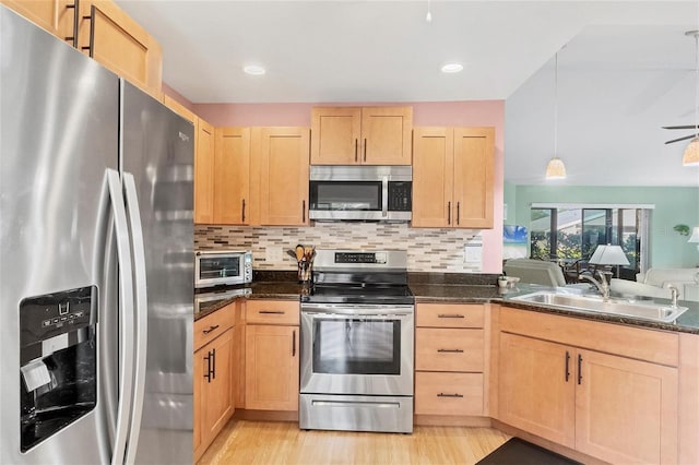 kitchen with appliances with stainless steel finishes, light brown cabinetry, decorative light fixtures, decorative backsplash, and sink