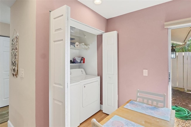 clothes washing area with light wood-type flooring and washing machine and clothes dryer