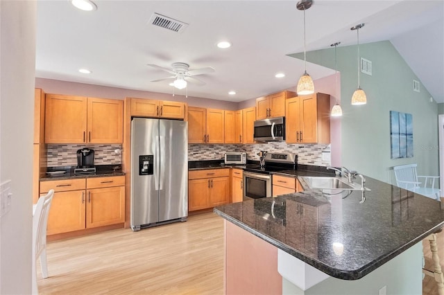 kitchen featuring kitchen peninsula, stainless steel appliances, light hardwood / wood-style flooring, decorative light fixtures, and sink