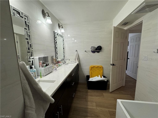 bathroom with hardwood / wood-style floors, vanity, and tile walls