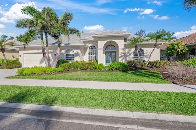 mediterranean / spanish-style home with a garage and a front lawn