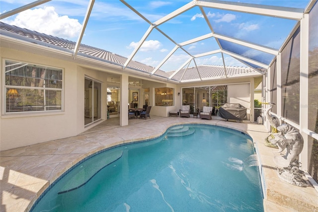 view of pool with pool water feature, a patio area, grilling area, glass enclosure, and an outdoor hangout area