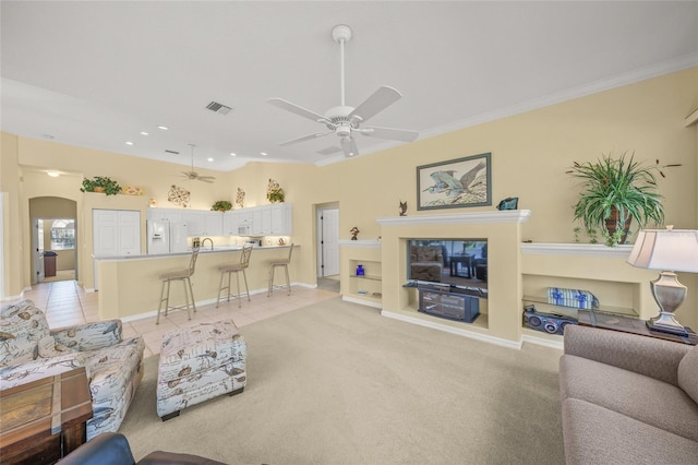 living room with light tile patterned flooring, ceiling fan, ornamental molding, and vaulted ceiling