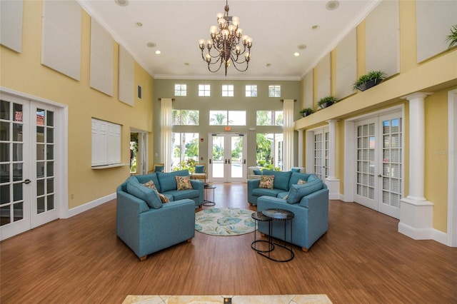 living room with ornamental molding, a towering ceiling, hardwood / wood-style floors, and french doors