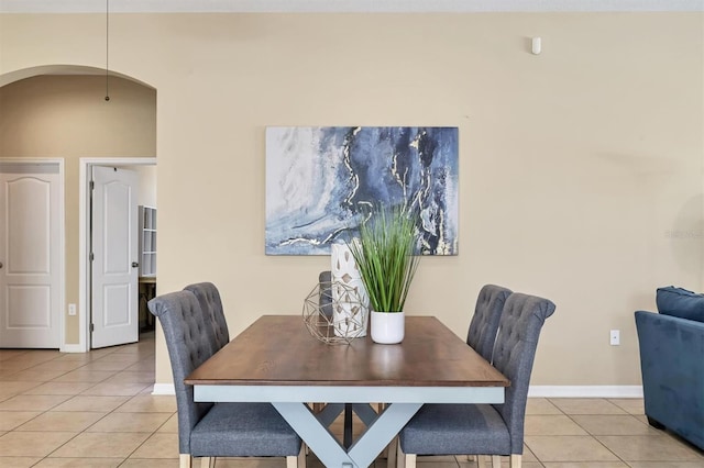 dining area with light tile patterned floors, baseboards, and arched walkways