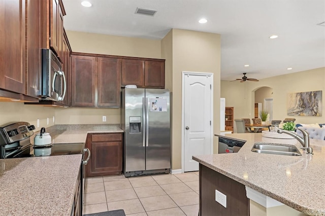 kitchen featuring light tile patterned floors, arched walkways, a sink, ceiling fan, and stainless steel appliances