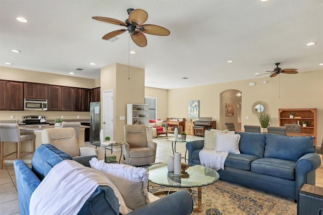 living room featuring light tile patterned flooring, recessed lighting, arched walkways, and a ceiling fan