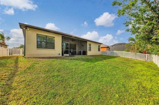 back of property featuring a lawn, a fenced backyard, and a sunroom