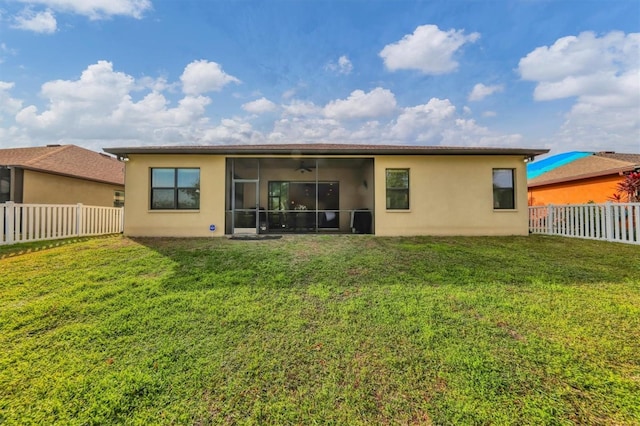 back of property with stucco siding, a lawn, a fenced backyard, and a sunroom