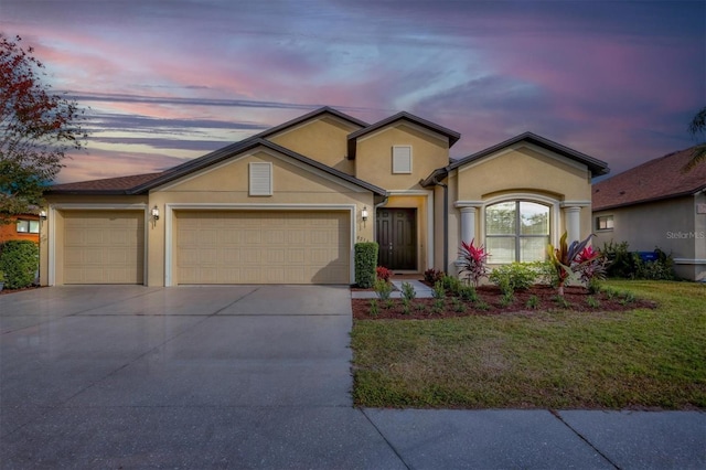 traditional-style home featuring stucco siding, a garage, concrete driveway, and a front yard