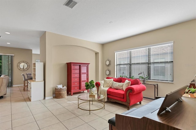 living room with light tile patterned floors, visible vents, and baseboards