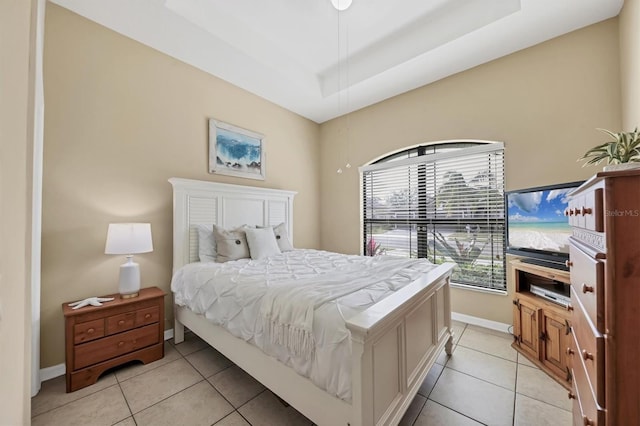 bedroom with a tray ceiling, baseboards, and light tile patterned flooring