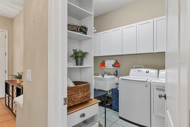 laundry room featuring cabinet space, light tile patterned floors, and washing machine and dryer