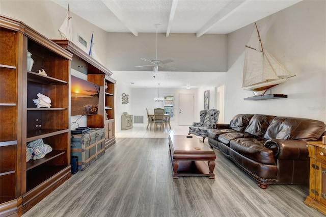 living room featuring a textured ceiling, a towering ceiling, beamed ceiling, ceiling fan, and hardwood / wood-style floors