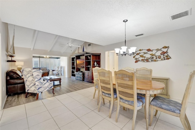 dining area featuring lofted ceiling with beams, ceiling fan with notable chandelier, light tile patterned floors, and a textured ceiling