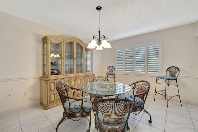 tiled dining space with a textured ceiling and a chandelier