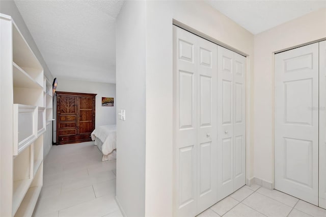 hall featuring light tile patterned floors and a textured ceiling