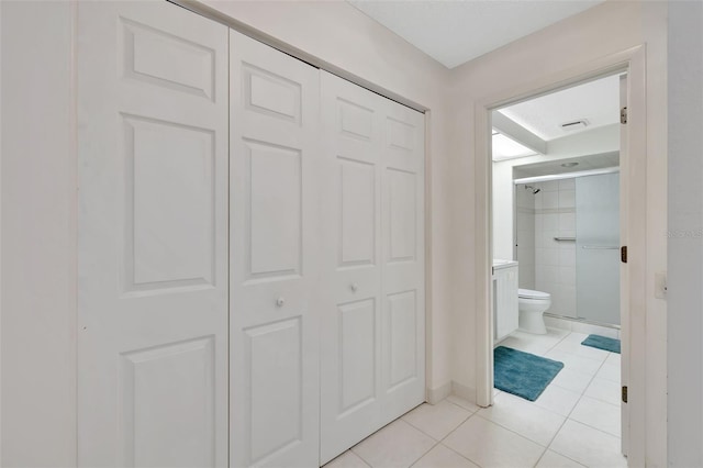 bathroom featuring an enclosed shower, tile patterned floors, and toilet