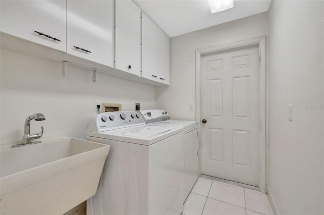 laundry room featuring sink, light tile patterned floors, cabinets, independent washer and dryer, and a textured ceiling