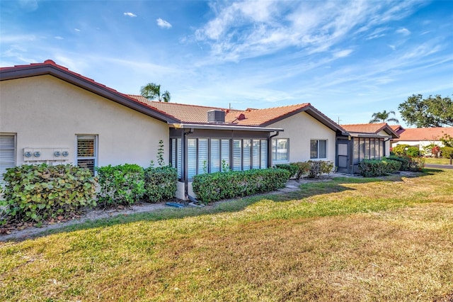 rear view of house featuring a sunroom and a lawn