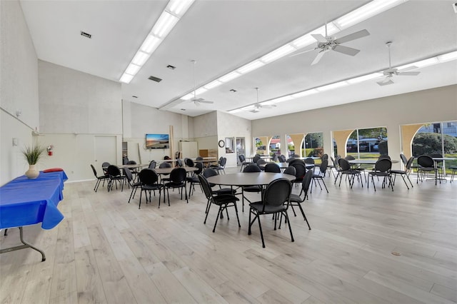 dining area featuring ceiling fan, a towering ceiling, and light wood-type flooring