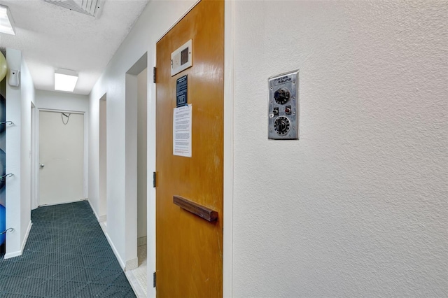 hall with a textured ceiling