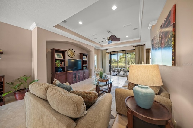 living room featuring crown molding, light tile patterned floors, a tray ceiling, and ceiling fan