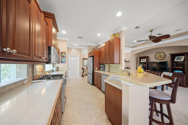 kitchen with appliances with stainless steel finishes, sink, a kitchen breakfast bar, kitchen peninsula, and crown molding