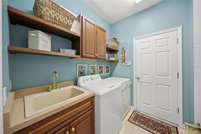 laundry area with light tile patterned flooring, cabinets, washer and clothes dryer, and sink