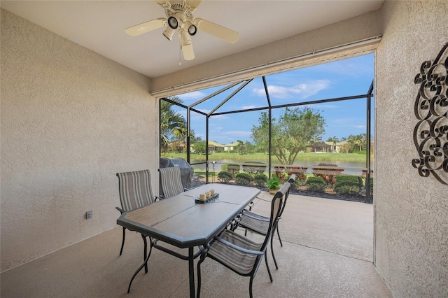 view of patio featuring a lanai, ceiling fan, and a water view