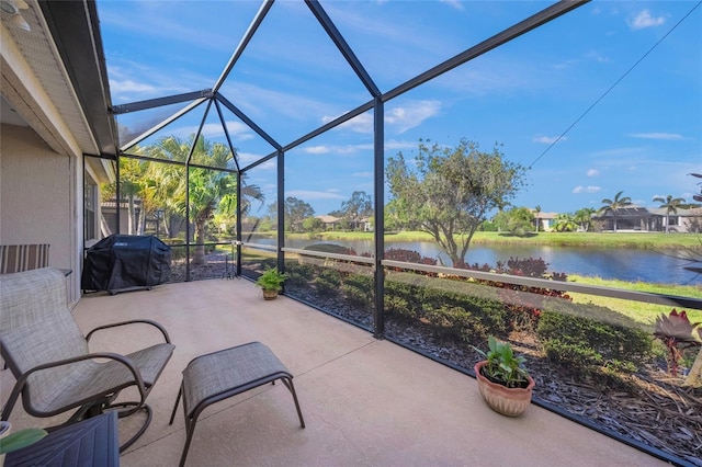 view of patio with a water view, grilling area, and glass enclosure