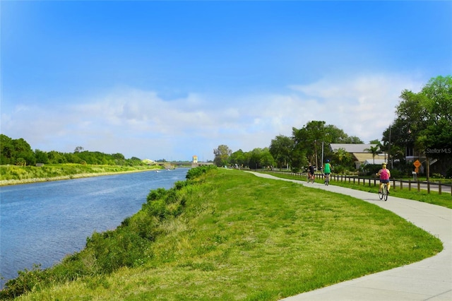 surrounding community with a water view and a lawn