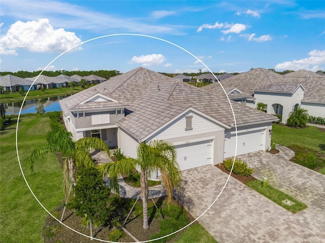 view of front of home featuring a garage, a front lawn, and a water view