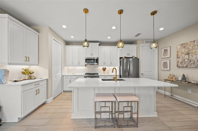 kitchen featuring sink, stainless steel appliances, white cabinets, and a center island with sink