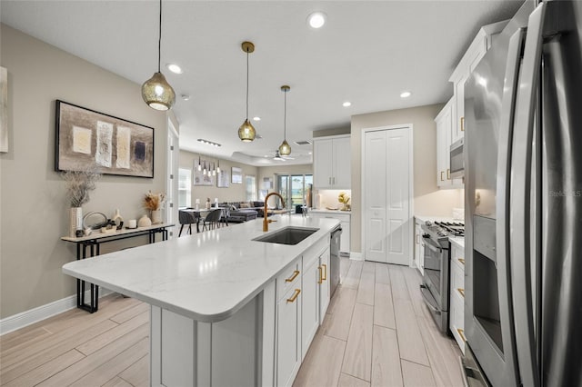 kitchen with sink, white cabinetry, pendant lighting, stainless steel appliances, and a kitchen island with sink