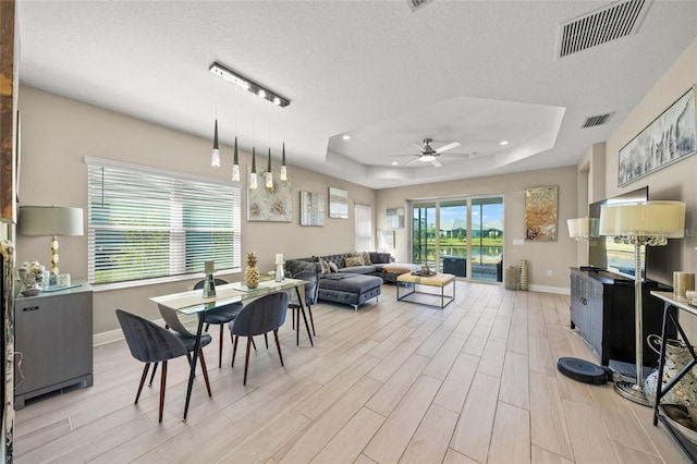 dining room featuring ceiling fan, a textured ceiling, and a tray ceiling