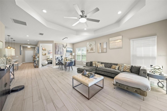 living room featuring a tray ceiling and ceiling fan