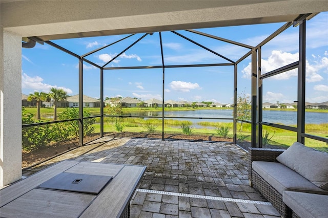 view of patio featuring glass enclosure and a water view