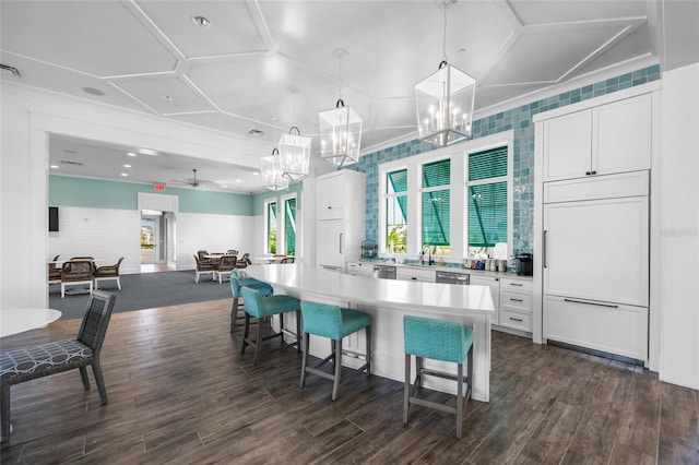 kitchen with pendant lighting, a kitchen breakfast bar, a center island, paneled refrigerator, and white cabinets